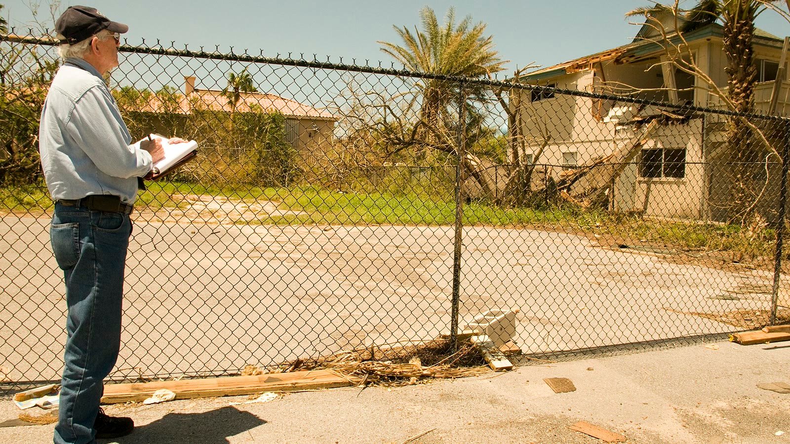 Inspector documenting damage to a house with a clipboard after a hurricane