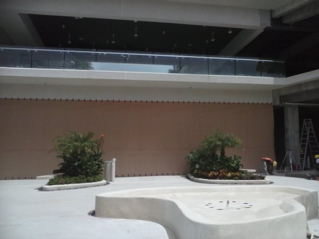 Fabric screen covering a wide opening behind planters and a fountain in a commercial courtyard.