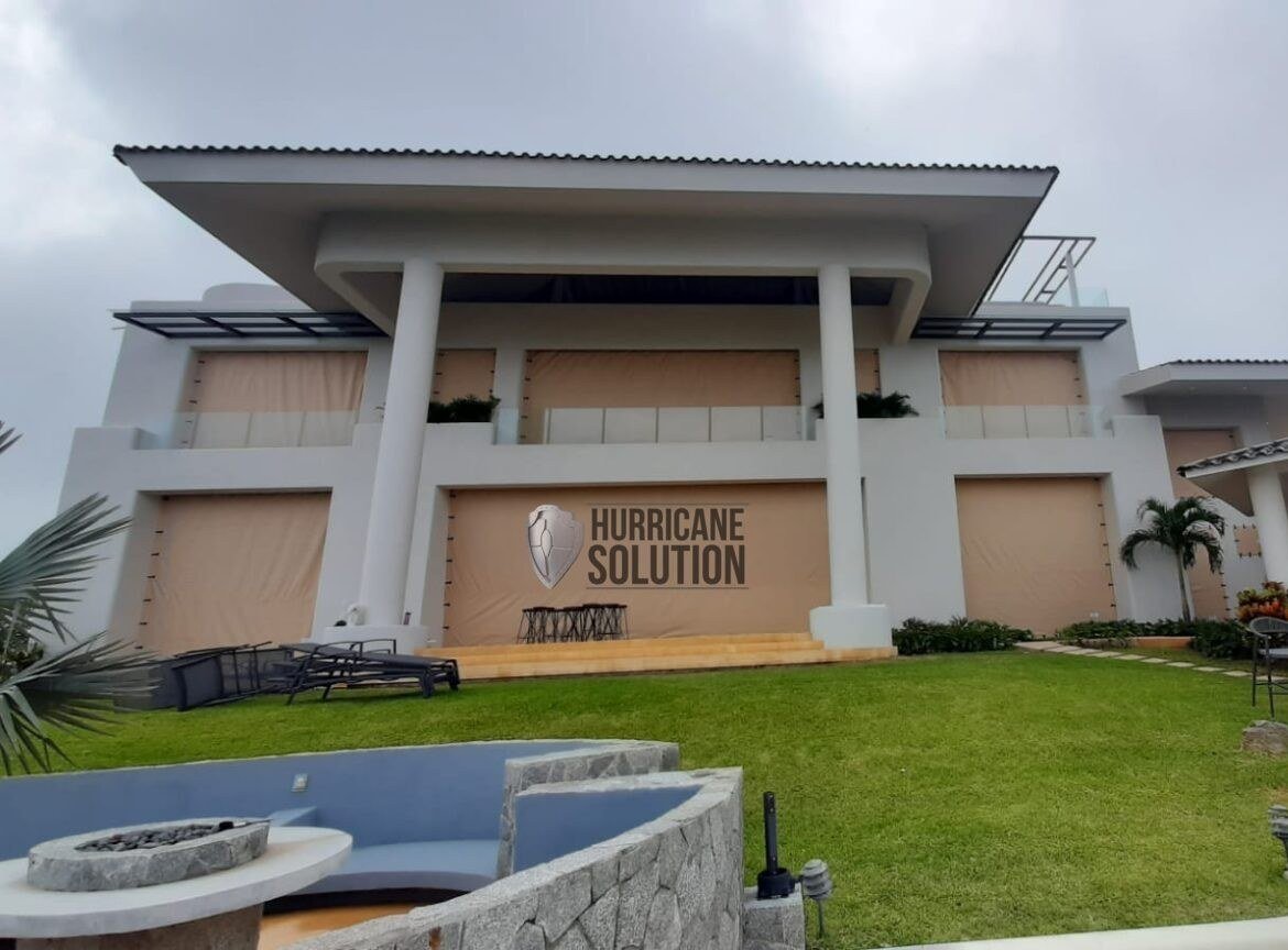 Two-story home facade with columns, a balcony and Hurricane Solution screens across doors and windows.