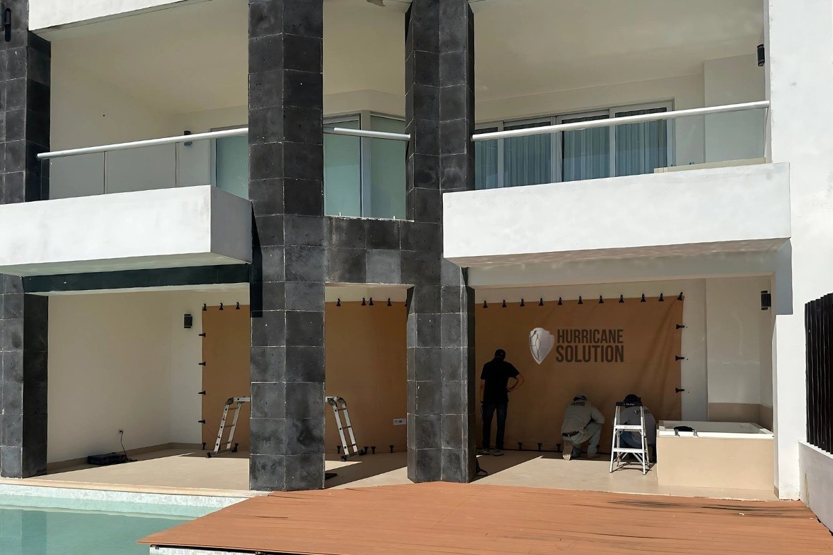 Work area with Hurricane Solution screens across lower openings of a modern home beside a pool.