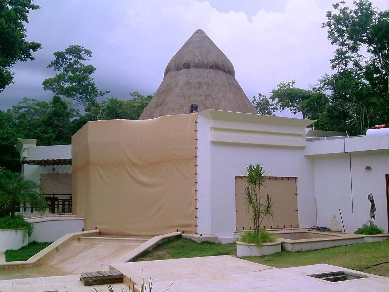 Hurricane Solution fabric stretched over a wide entrance in a white residence with a thatched roof.