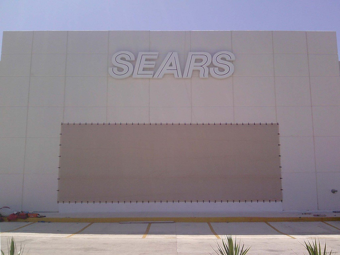 Front view of a Sears store with a wide fabric screen fastened around all four edges.