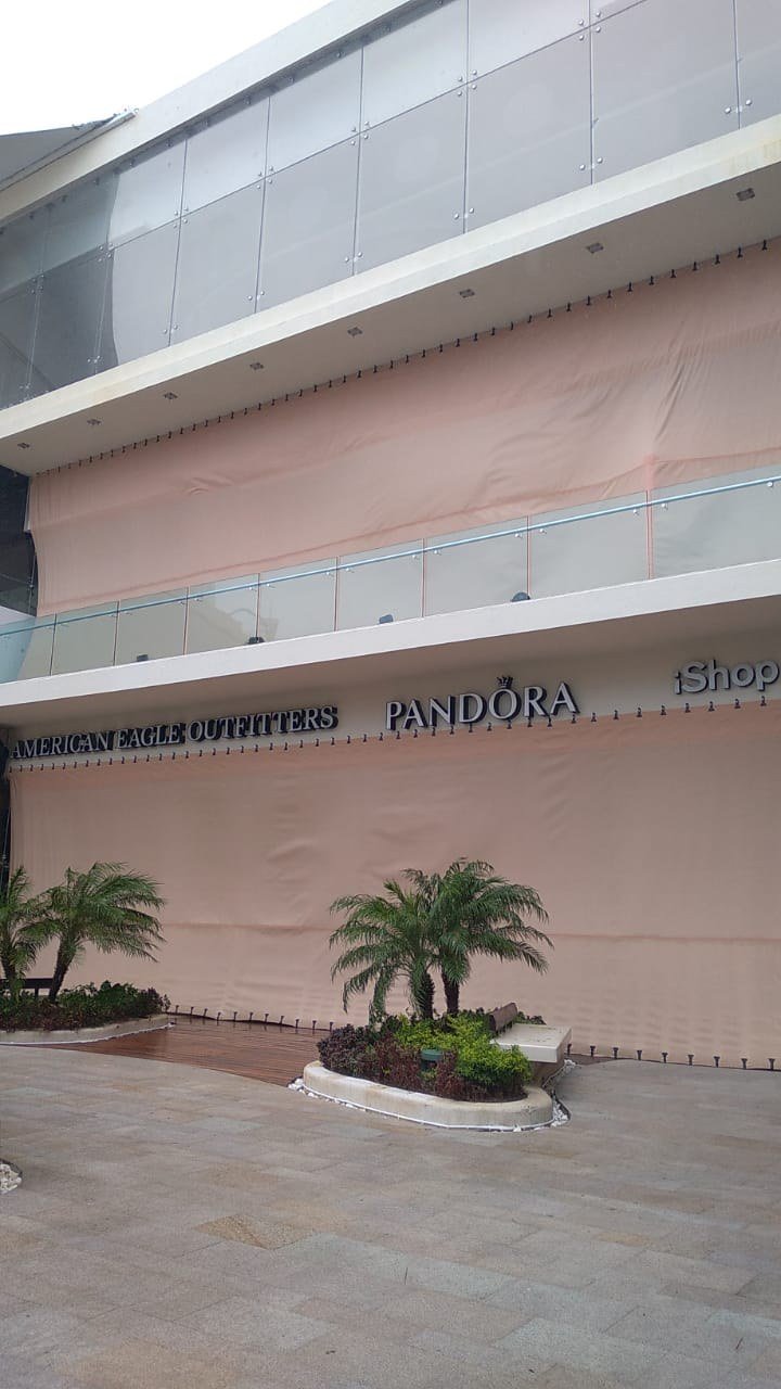 Fabric screens covering openings above shopping-center balconies and storefronts.