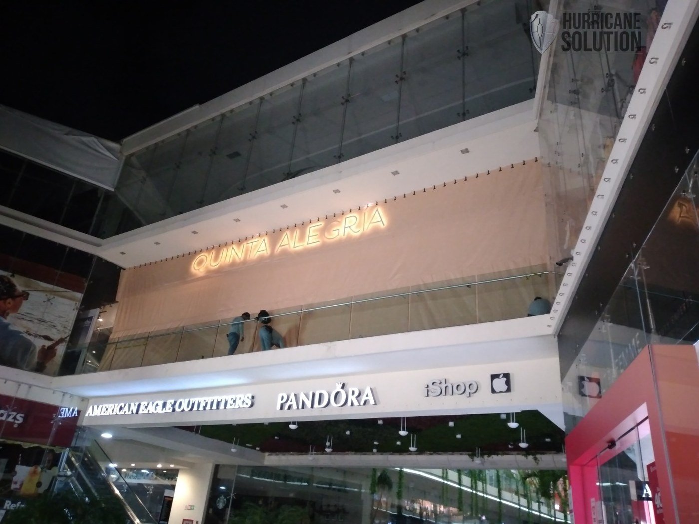 Hurricane Solution screen covering an upper-level shopping-center opening above stores and escalators.