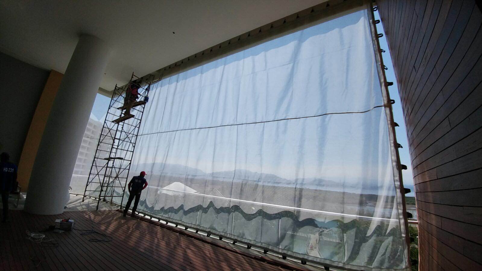 Instalación de una malla AquaGrid en una abertura interior alta con un trabajador y andamios.